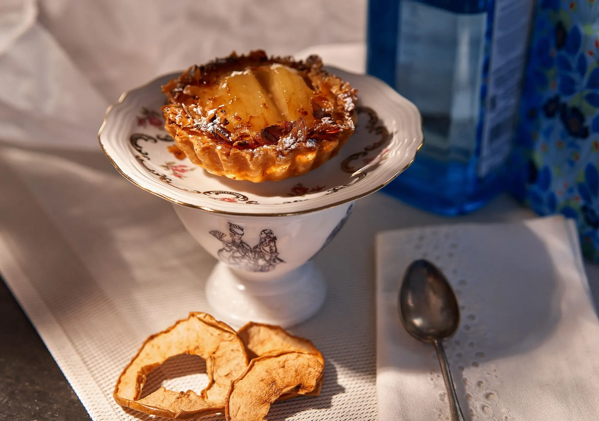 Tarte aux pommes présentée sur un compotier dans une lumière chaude